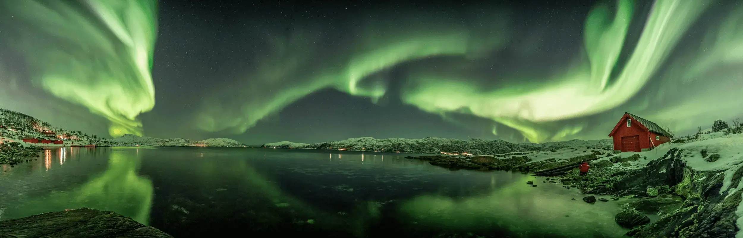 Green aurora ribbons above snow-covered mountains
